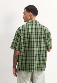 YOURTURN OVERSIZE UNISEX - Blusa com botões - green/black
