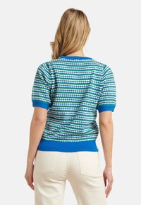 Korte mouw gebreide trui met horizontale strepen in blauw, groen en wit. Heeft een ribbelkraag en -zoom in het blauw, gemaakt van zacht materiaal.