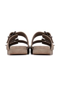 Sandali in suede marrone con due cinturini regolabili, suole piatte e design minimalista. Famosi per le fibbie rotonde che assicurano una perfetta vestibilità.