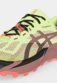 Chaussure de trail Asics Trabuco 14 jaune et rose avec lacets noirs, semelle texturée et amorti FF Blast+Max visible sur la semelle intermédiaire.