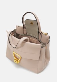 Sac à main en cuir rose pâle avec une forme structurée, doté d'un fermoir en métal doré, de poignées doubles et d'un intérieur en tissu. Fermeture zippée.