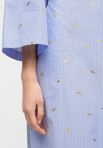 Φόρεμα από ύφασμα με μπλε και άσπρες ρίγες και χρυσά σχέδια πελαργών, με φαρδιά, μανσέτες και πλαϊνή τσέπη. Υλικό από υφή βαμβακιού.