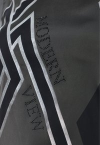 Zwarte stof met geometrische zilveren lijnen en glanzende zwarte rhinestones die "MODERN VIEW" spellen. Gladde textuur met opmerkelijke versieringen.