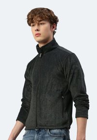 Dunkelgraue Fleecejacke mit hohem Kragen, durchgehendem Reißverschluss und seitlichen Taschen. Verfügt über eine weiche Textur und schmal geschnittene Bündchen.