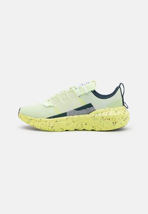 Light green athletic shoe with speckled yellow sole, white laces, black pull tab, and white striped logo on the side.