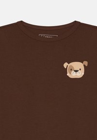 Bruine t-shirt met korte mouwen van zachte stof, met een cartoon honden gezicht graphic op de linkerborst. Ronde halsontwerp.