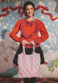 Piros pulóver szív alakú fodorral, fekete szoknya, valamint virágmintás bevásárlótáska szív- és levélmintákkal. Sima anyag, erős fogantyúk.