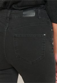 Svarta denimjeans som har en bakficka med en subtil sömdetalj och en läderlapp vid midjan med varumärkesinskrift.