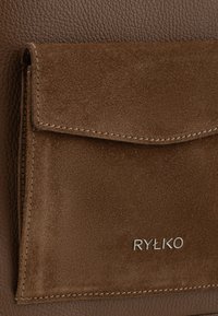 Borsa in pelle e suede marrone con tasca frontale a pattina caratterizzata da texture contrastanti e il nome del marchio "RYŁKO" in lettere argentate.