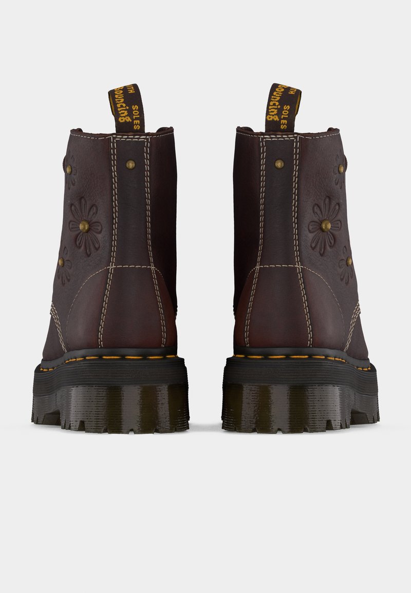 Pair of dark brown leather boots with floral embossing, yellow stitching, thick black soles, and black-yellow pull tabs at the back.