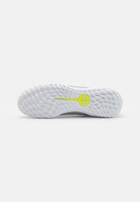 White athletic shoe sole with textured, dotted pattern. Features a prominent green logo accent. Robust, lightweight design for traction.
