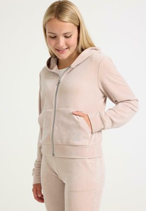 Roze velours zip-up hoodie met een capuchon, voorkwesten en subtiele geborduurde logodetail op de borst. Zachte textuur en een getailleerd ontwerp.