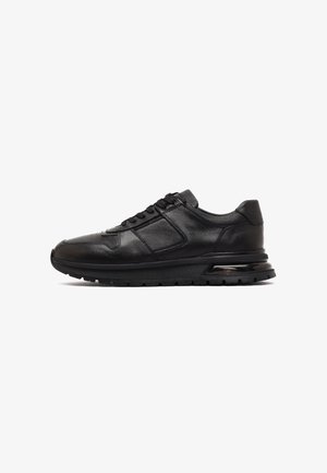 Zwarte leren sneaker met vetersluiting aan de voorkant, sportieve zool en gevoerde kraag, gezien vanaf de zijkant tegen een witte achtergrond.