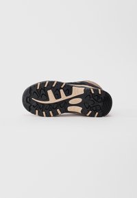Sole of a black and beige hiking shoe with deep treads labeled "CMP Full On Grip" on a white background.