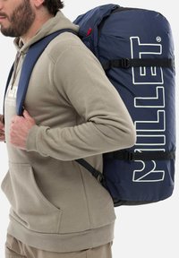 Sac  à dos bleu marine avec un grand logo "MILLET" blanc, des bretelles rembourrées et des boucles ajustables. Il est doté d'un tissu durable et d'une forme épurée.