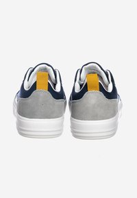 Sneakers blu navy e grigi con parte superiore in suede e mesh, suola in gomma bianca e un grande tassello giallo sul tallone per una facile calzata.