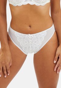 Culotte en dentelle blanche avec un motif floral, des bords festonnés et un petit nœud à l'avant. Matériau transparent et finition lisse.