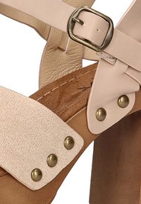 Sandal de cuero beige claro con una amplia correa texturizada, remaches de bronce y cierre de hebilla. Cuenta con una suela de corcho y un tacón robusto.