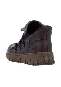 Chaussure en cuir marron avec une surface texturée, ornée d'accents noirs, d'un col rembourré et d'une semelle en caoutchouc épaisse et rainurée.