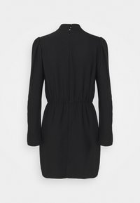 Robe courte noire à manches longues avec taille froncée, épaules bouffantes, col haut et fermeture éclair dans le dos.