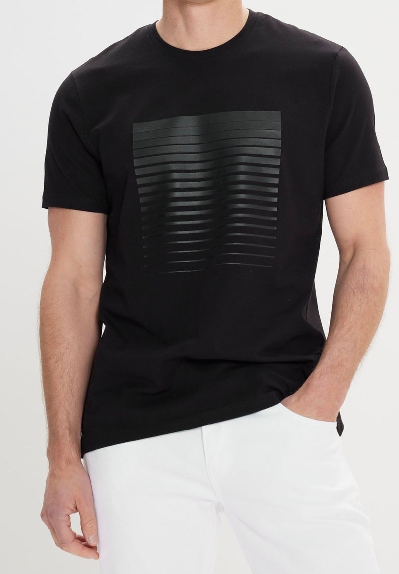 Camiseta negra de manga corta con un patrón de líneas horizontales texturizadas en tonos de negro en la parte delantera, confeccionada en suave tela de algodón.
