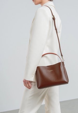 Sac à main en cuir marron avec une forme structurée, une fine anse pour l'épaule et une poignée supérieure. L'avant présente un branding en relief et un design minimal.