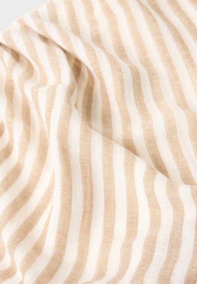 Μπεζ και λευκό ριγέ μαλακό ύφασμα με ορατή υφή ύφανσης, ελαφρώς τσαλακωμένο και κρεμασμένο, εμφανίζοντας ένα φυσικό ρέον μοτίβο.