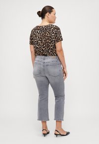 Leopard print cropped shirt with short sleeves, paired with gray high-waisted jeans and black slingback shoes. Simple design, casual look.