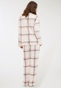 Set di pigiama a quadri realizzato in un tessuto leggero con motivi a rete in rosa, marrone e bianco; include una maglietta a maniche lunghe dalla vestibilità ampia e pantaloni.