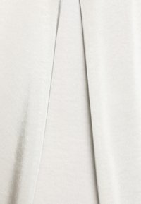 Tissu gris clair à texture douce, présentant un design plissé. La surface semble lisse, avec une légère brillance et sans motifs visibles.