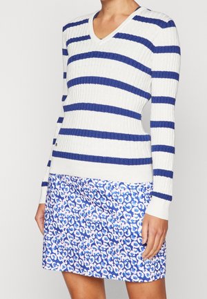 Pull en maille côtelée rayé bleu et blanc avec un col en V, associé à une jupe imprimée léopard bleu et rose au design ajusté.