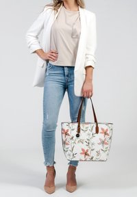 Sac fourre-tout à motif floral avec des poignées en cuir marron, présentant un fond blanc et des nuances de vert, rose et orange. Design élégant et spacieux.