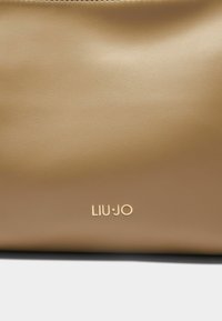 Tanana sintetička kožna torba s glatkom teksturom i zlatnim logotipom "LIU•JO" sprijeda. Ima zatvaranje na zip na vrhu.