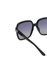 Black sunglasses with a square frame, gradient lenses, and a logo on the temple. Smooth surface and sleek design.