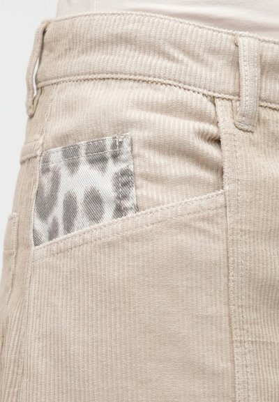 Υφασμάτινο ρεγιόν μπεζ με υφή, διαθέτοντας μια μικρή τσέπη με μοτίβο λεοπάρ στο πίσω μέρος.