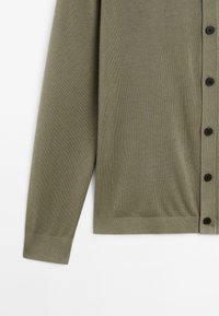 Cardigan en maille vert olive à manches longues avec boutons noirs, poignets et ourlet côtelés, présenté sur fond blanc.