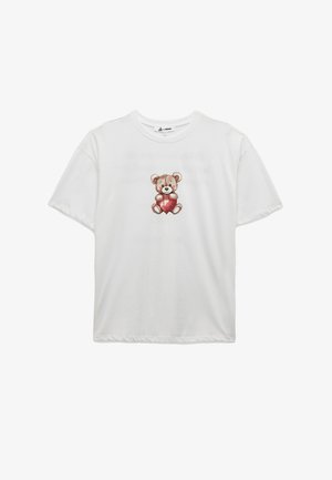 Camiseta de algodón blanca con un gráfico de un oso sosteniendo un corazón rojo. Mangas cortas, corte holgado, escote redondo. Textura suave.