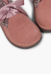 Stivaletti alla caviglia in suede rosa con un accento di glitter, fiocco in nastro di satin e cuciture a contrasto. Progettati con una suola in gomma per garantirne la durevolezza.