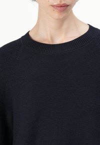 Μπλε ναυτικό πλεκτό πουλόβερ με στρογγυλή λαιμόκοψη και ριγωτό μανίκι, με υφή στη σύνθεση του και εφαρμοστή γραμμή.