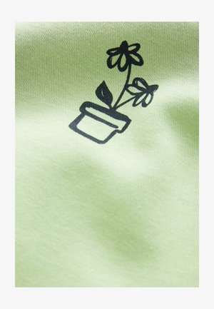 Melna līniju māksla ar podā esošu augu un divām ziediem uz maiga, gaisīgi zaļa auduma fona. Dizains ir centrāli novietots un skaidrs.