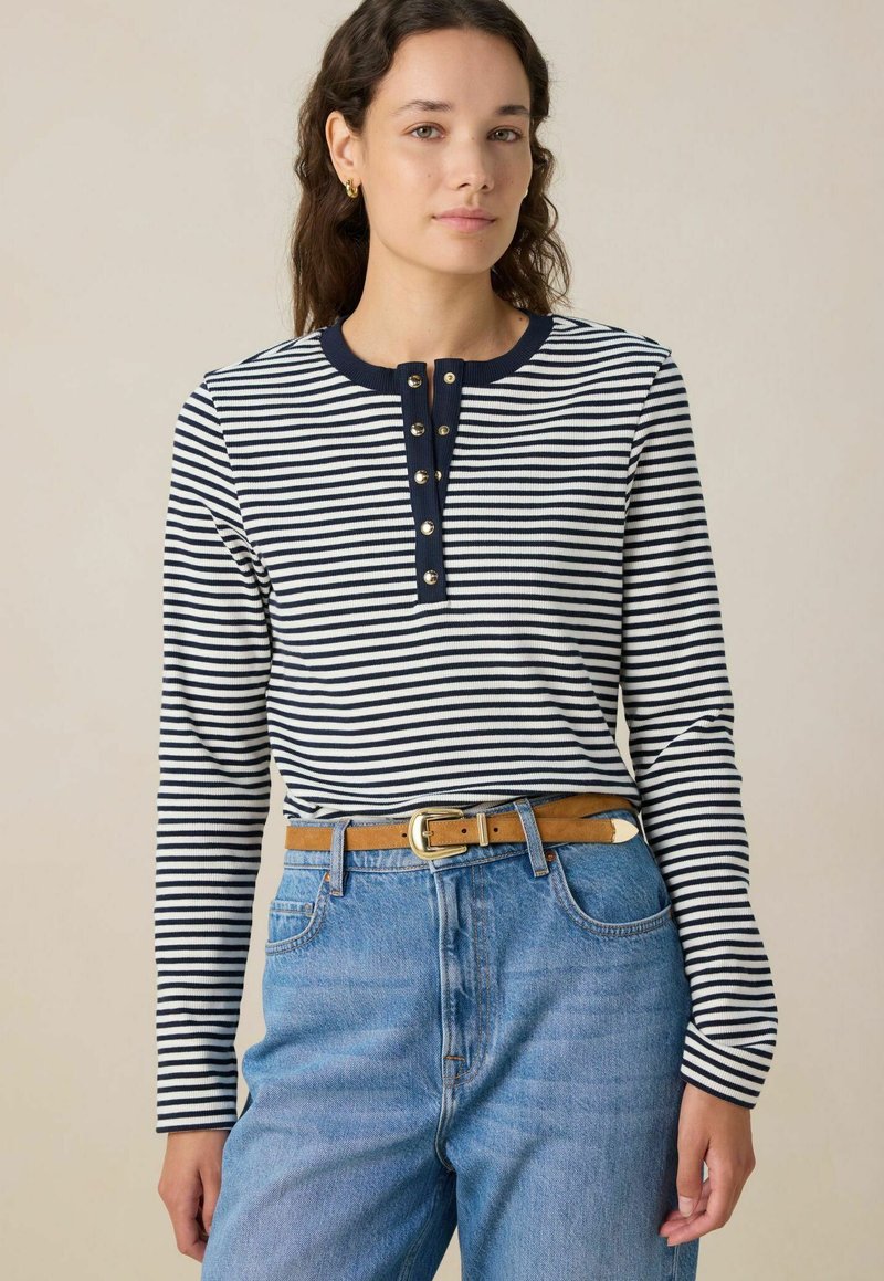 Langarm gestreept T-shirt in marineblauw en wit, met een ronde hals en een knoopsluiting. Gekocht met lichtblauwe jeans en een tan kleurige riem.