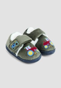 Vihreät fleece-sandaalit valkoisella vuorilla, joissa on brodeerattu punainen traktori ja siniset yksityiskohdat. Velcro-kiinnitys, tasapohja, pehmeä rakenne.