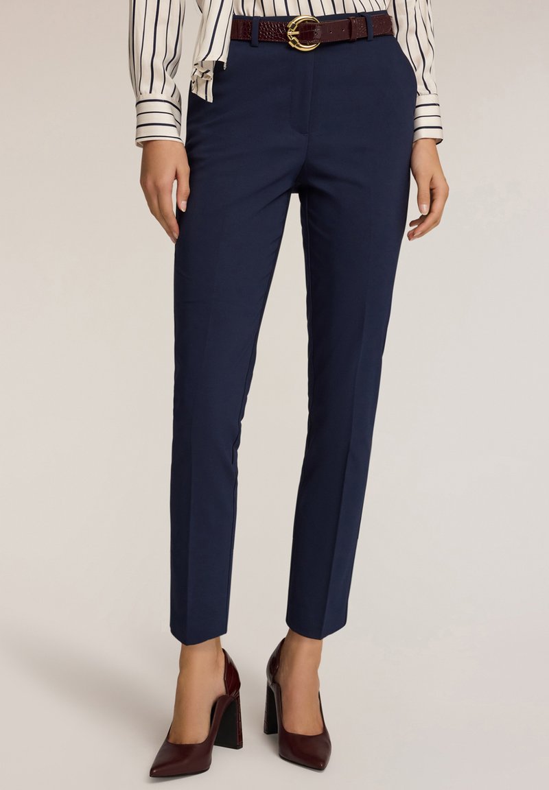 Námořnické modré kalhoty na míru s hladkým materiálem, úzkým střihem a páskem střední výšky, doplněné texturovaným vínovým opaskem se zlatou sponou.
