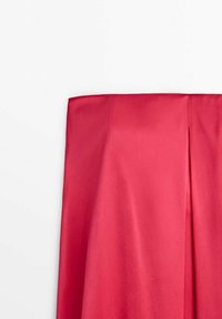 Tissu rouge vif, lisse avec une légère brillance douce. Le vêtement présente un bord supérieur droit et un pli subtil pour ajouter de la dimension.