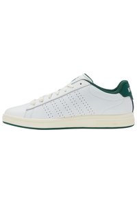 Adidași albi cu o finisare din piele neted�ă, accente verzi pe guler și călcâi, detalii perforate pe lateral și o talpă din cauciuc texturată.