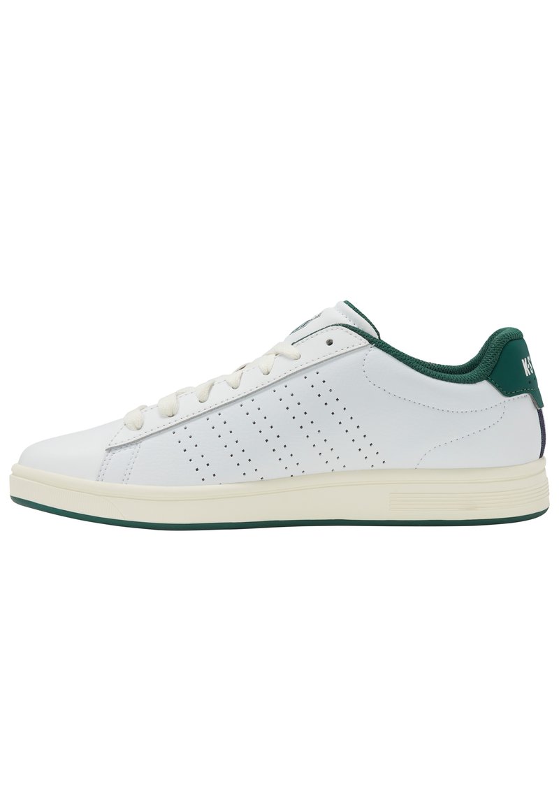 Adidași albi cu o finisare din piele netedă, accente verzi pe guler și călcâi, detalii perforate pe lateral și o talpă din cauciuc texturată.