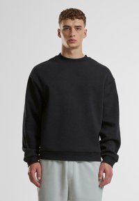 Schwarzes Sweatshirt aus Baumwollmischung. Mit Rundhalsausschnitt, langen Ärmeln und überschnittenen Schultern. Glatte Textur, gerippte Bündchen und Saum.