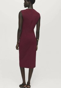 Burgundy kroppsnära klänning med en strömlinjeformad silhuett, ärmlös design, knälång nederkant och mjuk tygstruktur.