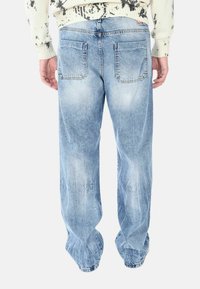 Jeans in denim blu chiaro con vestibilità rilassata, caratterizzati da dettagli sbiaditi, due tasche posteriori e orli sfilacciati.