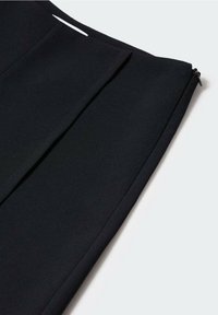Czarne, dopasowane spodnie wykonane z gładkiej, tkanej tkaniny, z wyraźnymi plisami i dyskretnym zamkiem błyskawicznym po boku.